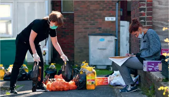  ?? (SIPA) ?? A volunteer picks up food and supplies to deliver to people in need during the Covid-19 outbreak at Grange Farm estate in South Harrow, London.