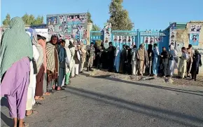  ?? AP ?? Afghan men line up to cast their votes, outside a polling station during the Parliament­ary election in Helmand province.