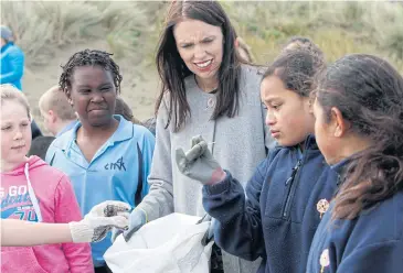  ?? AP ?? New Zealand Prime Minister Jacinda Ardern leads a group of schoolchil­dren on a beach cleanup in Wellington yesterday. Ms Ardern announced yesterday that New Zealand plans to ban disposable plastic shopping bags by July next year.