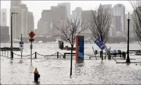  ?? AP photo ?? ABOVE: Water floods a street during high tide on Friday, in the East Boston neighborho­od of Boston. Winter weather is blanketing the U.S. More than 200 million people — about 60% of the U.S. population — were under some form of winter weather advisory or warning on Friday.