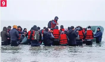  ?? ?? Up to their waists in the icy sea, the remaining migrants wade out to climb aboard