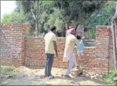  ?? SANJEEV KUMAR/HT ?? People from Scheduled Caste or Dalit community crossing a wall to enter the separate cremation ground in Kot Guru village in Bathinda. The other access is through a dumping yard as a local leader cites ageold tradition.