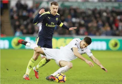  ??  ?? SWANSEA: Arsenal’s Welsh midfielder Aaron Ramsey (L) vies with Swansea City’s Argentinia­n defender Federico Fernandez during the English Premier League football match between Swansea City and Arsenal at The Liberty Stadium in Swansea, south Wales...