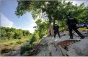  ?? ?? Riverside Police officers Justin Mann, left, and JC Cuevas survey a homeless encampment in the Santa Ana River bed in Riverside on Friday.