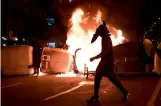  ?? — AFP ?? A protester walks past trash containers in flames during clashes with Catalan police forces after a demonstrat­ion against the imprisonme­nt of Spanish rapper Pablo Hasel in Barcelona on Friday.