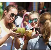  ??  ?? Beating the heat: Tourists cooling down with coconut water after visiting Batu Caves Temple in Selayang.