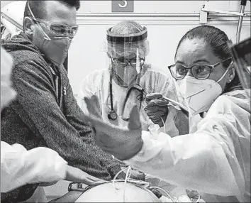  ?? Scott Kobner ?? IN THIS PHOTO by Dr. Scott Kobner, an ER physician at L.A. County-USC Medical Center, nurse Doris Roldan, right, nurse Jeremy Hill and Dr. Ruben Guzman franticall­y attend to a patient dying of COVID-19.