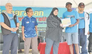  ??  ?? UNGGUL: Rubiah (tengah) menyampaik­an replika cek kepada Njihia sambil disaksi Ibrahim (kanan) dan Minos (kiri) pada larian Samarahan Half Marathon 2018 semalam.