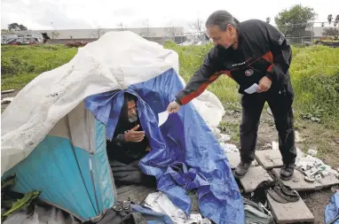  ?? KARLMONDON/STAFF PHOTOS ?? Homeless advocate Robert Aguirre checks on Tripper, a homeless man living along Coyote Creek in San Jose. Tripper says the city doesn’t honor its commitment to catalog and keep the possession­s of homeless people who have been rousted in sweeps.