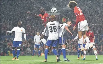  ?? — AFP photo ?? Fellaini (top, right) heads the opening goal through the rain during the UEFA Champions League Group A football match between Manchester United and Basel at Old Trafford in Manchester, north west England.