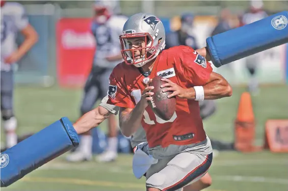  ?? STAFF PHOTO BY MATT STONE ?? SKILLFUL DODGE: Quarterbac­k Jimmy Garoppolo carries the ball as he avoids being hindered by an assistant coach’s pads during a drill yesterday in Foxboro. In a radio appearance, Garoppolo also ducked the issue of Tom Brady’s absence from practice.