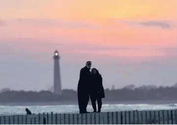  ?? CHARLES REX ARBOGAST/AP ?? Visitors to Cape May, New Jersey, watch the sunset behind the Cape May Lighthouse in April. With the ocean on one side and grand Victorian homes on the other, Cape May offers a vacation location with expansive views.