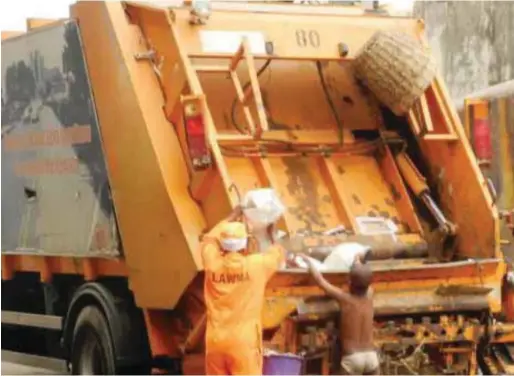  ??  ?? A LAWMA official collecting waste from the streets