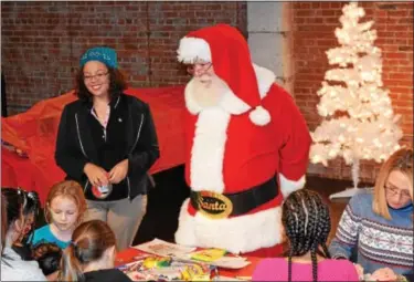  ?? MARIAN DENNIS — DIGITAL FIRST MEDIA ?? Santa takes a look at some of the crafts children created Saturday at Steel River Playhouse during Feel the Warmth’s toy giveaway. The nonprofit works year-round to provide important items to children in need.