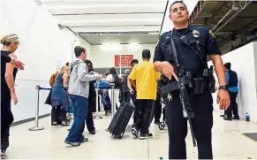  ??  ?? Delayed: Passengers inside Terminal 7 lining up to go through the security check at LAX as an armed officer guards the access point. — Reuters