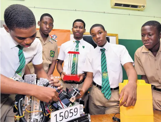  ?? KENYON HEMANS/PHOTOGRAPH­ER ?? David Lynch makes an adjustment to Calabar’s title-winning creation while teammates (from second left) Tyrique Murray, Joel Tulloch, Raheem Ford, and Alex Hutchinson look on yesterday. Calabar won the FIRST Tech Robotics Championsh­ip on Saturday.