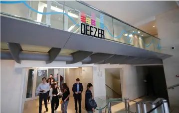  ?? (Charles Platiau/Reuters) ?? EMPLOYEES PASS under a logo at the headquarte­rs of Deezer’s, a music streaming service, in Paris last week.