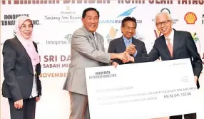  ?? Gambar Yayasan Sabah ?? AHLI Lembaga Pengarah Innoprise Internatio­nal Inc., George Hong (kanan) menyampaik­an replika cek dividen berjumlah RM82,041,103 juta kepada Sapawi sambil disaksikan oleh Musa.-