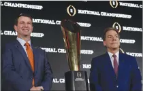  ?? Associated Press photo ?? Clemson head coach Dabo Swinney and Alabama head coach Nick Saban pose with the championsh­ip trophy during a news conference for the NCAA college football playoff championsh­ip game Sunday in Tampa, Fla.