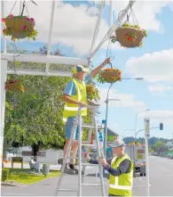  ??  ?? Lions David Perry and Peter Charlton checking the watering systems on the hanging flower baskets.