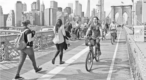  ??  ?? Cycling on the Brooklyn Bridge from downtown Manhattan in New York. Building bike paths, handing out free helmets and a bike-sharing scheme going from strength to strength: If some are still nervous about navigating bottleneck traffic in the shadow of...