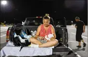  ?? DAVID GOLDMAN / AP ?? Lorrainda Smith sits with her 2-day-old son, Luke, on Monday as she contemplat­es with her husband, Wilmer Capps (right) sleeping in their truck in a parking lot after their home was damaged by Michael.