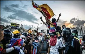  ?? MERIDITH KOHUT / THE NEW YORK TIMES ?? Anti-government protesters celebrate after retaking the main highway through Caracas on May 26. Nearly every day for more than three months, a ragtag group of Venezuelan protesters have taken to the streets.