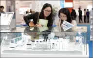  ?? XIAO XIN / FOR CHINA DAILY ?? Visitors look at 3-D-printed products at the Roche Group booth at a technology fair in Shanghai.