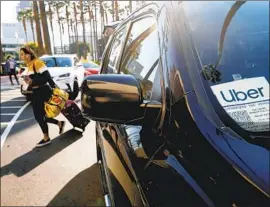  ?? Francine Orr Los Angeles Times ?? IN TRYING to comply with the stringent definition of independen­t work establishe­d by Assembly Bill 5, Uber is experiment­ing with features it has dismissed as unworkable. Above, a woman exits an Uber ride at Union Station last year.