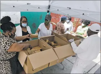  ??  ?? Kiana Muschett-Owes (left), owner of Katie O’s, helps to distribute food through volunteers at the Good Shepherd Church on July 11 in the Brooklyn borough of New York.