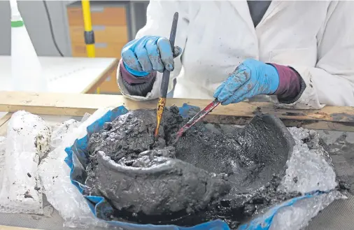  ??  ?? PAINSTAKIN­G: An archaeolog­ist cleans mud from the 2,000-year-old wooden bowl found at the Cairns Broch site on South Ronaldsay