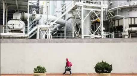  ?? ISAAC LAWRENCE/AFP ?? A woman walks past a gas refinery in Hong Kong’s To Kwa Wan district in Janaury.