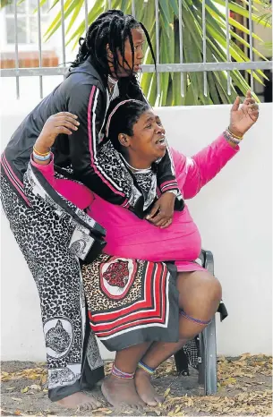  ?? Pictures: FREDLIN ADRIAAN ?? IN SHOCK: Nonzalisek­o Sikunyana cries while being comforted by her friend, Bulelwa Mgijima, as they watch the house burn