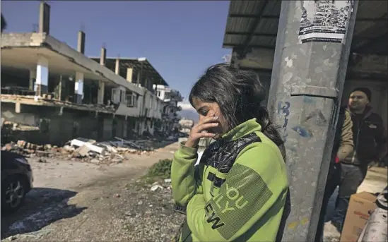  ?? Khalil Hamra Associated Press ?? A GIRL stands next to destroyed buildings in Antakya, Turkey, one of the cities hardest hit by the 7.8 earthquake.