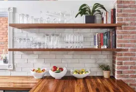  ??  ?? Right: Open wood shelving offers an airy alternativ­e to upper-level cabinets, while colour and personalit­y come by way of the well-loved books on display