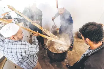  ?? — AFP photos ?? Volunteers cook together portions of the traditiona­l Libyan dish “Bazin”, which consists of a dough made with barley, water, and salt in the coastal city of Tajura east of Tripoli, to be distribute­d to needy families during the Muslim holy fasting month of Ramadan.