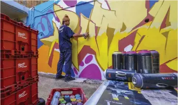  ?? — Bernama photo ?? Muhamad Fakhrul Akmal puts some finishing touches on his artwork along the pedestrian lane at Presint 8.