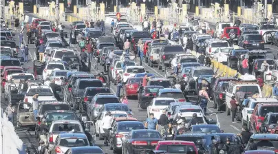  ?? PHOTO: GETTY IMAGES ?? Gridlock . . . People attempting to cross into the United States wait by their vehicles as the San Ysidro port of entry stands closed at the USMexico border in Tijuana yesterday. Migrants circumvent­ed a police blockade as they attempted to approach the El Chaparral port of entry and US Customs and Border Protection temporaril­y closed the two border crossings in response.