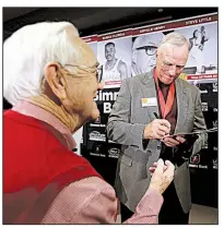  ?? Arkansas Democrat-Gazette/THOMAS METTHE ?? Former Razorback Joe Ferguson (right) signs an autograph for Tommy Fisher of Maumelle after the Southwest Conference Hall of Fame ceremony during the Little Rock Touchdown Club meeting Monday at the Embassy Suites in Little Rock.