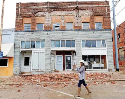  ?? [PHOTO BY JIM BECKEL, THE OKLAHOMAN ARCHIVES] ?? A television reporter shoots video as she walks past a damaged building in downtown Cushing after it was rocked with a large earthquake on Nov. 6, 2016.