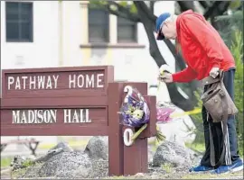  ?? Josh Edelson Associated Press ?? RESIDENT Tom Parkinson places f lowers at a sign for the Pathway Home at the Veterans Home of California in Yountville. About 1,000 vets live at the complex.