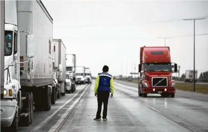  ?? Photos by Marie D. De Jesús / Staff photograph­er ?? A traffic controller makes sure truckers don’t cross into wrong lanes as they approach the customs area in Mexico before crossing into the United States from Nuevo Laredo last week.