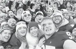  ?? AP ?? Aidan Hutchinson takes a selfie with family and fans after Michigan’s win over Ohio State on Nov. 27 in Ann Arbor, Mich.