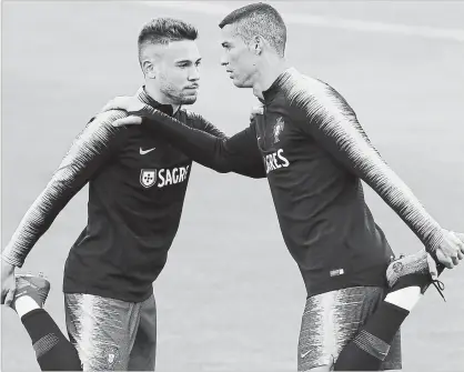  ?? ARMANDO FRANCA THE ASSOCIATED PRESS ?? Portugal’s Cristiano Ronaldo, right, stretches with teammate Raphael Guerreiro during training in Oeiras, outside Lisbon, on Monday.