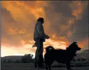  ?? Helen H. Richardson / The Denver Post ?? Calista Morrill, walking with her dogs Lucy, in front and Ollie, not pictured, watches smoke from the East Troublesom­e Fire become lit by the setting sun on Wednesday in Lyons. Morrill, who lives in Lyons, has packed her bags in case she needs to be evacuated for the Calwood Fire.
