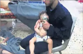  ?? AFP PHOTO ?? An image grab taken from a video released by the Syrian civil defence in Douma shows an unidentifi­ed volunteer holding an oxygen mask over a child’s face at a hospital following a reported chemical attack on the rebel-held town on Sunday.