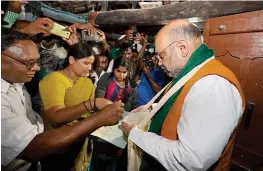  ?? — PTI ?? BJP president Amit Shah joins the party’s statewide door- to- door campaign, “Mushti Dhanya Sangrah Abhiyana”, at Mandya district’s Chinnenaha­lli village in Karnantaka on Saturday.