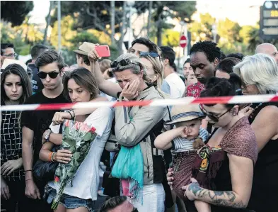  ?? LAURENT CIPRIANI / THE ASSOCIATED PRESS ?? People gather at a makeshift memorial to honour victims of Thursday’s attack, close to the area where a truck mowed through crowds gathered along a seaside promenade in the French Riviera for Bastille Day fireworks.