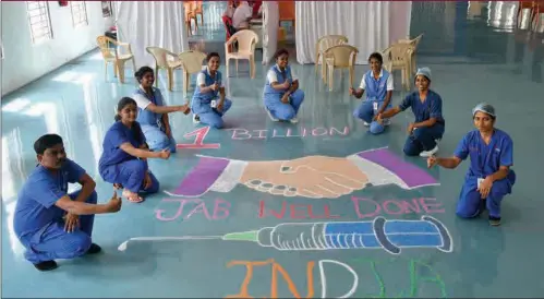  ?? ?? Medics pose next to a rangoli on the floor of the Ramaiah Hospital in Bangalore on October 21, 2021, as they celebrate India administer­ing its billionth Covid-19 vaccine dose.