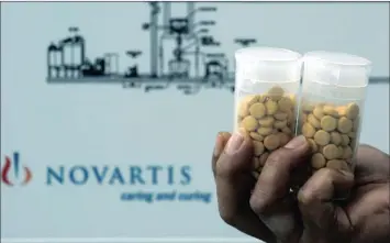  ?? PHOTO: BLOOMBERG ?? A worker holds containers of test tablets made in the Novartis Pharma Manufactur­ing facility in Singapore. Novartis is considerin­g asset sales that could raise $50 billion, perhaps freeing funds for another mega deal.